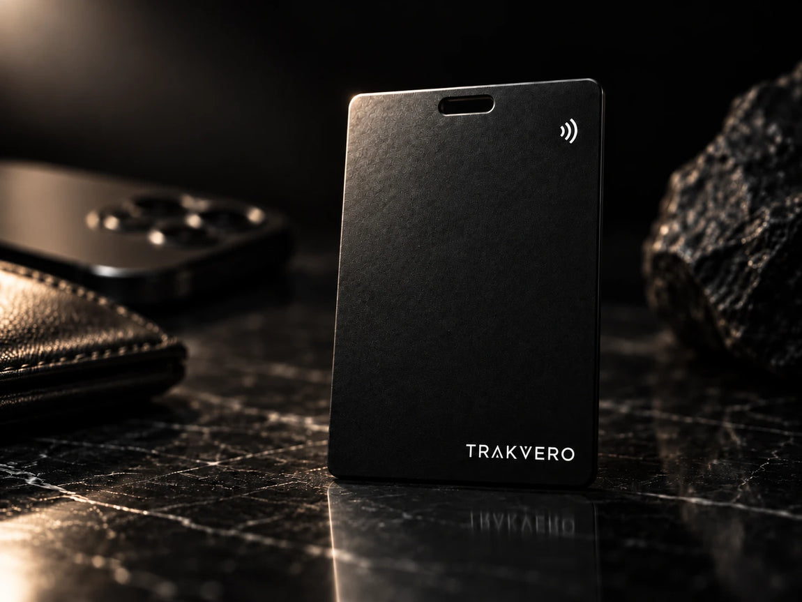 TRAKVERO tracker card standing on dark marble beside a wallet and phone